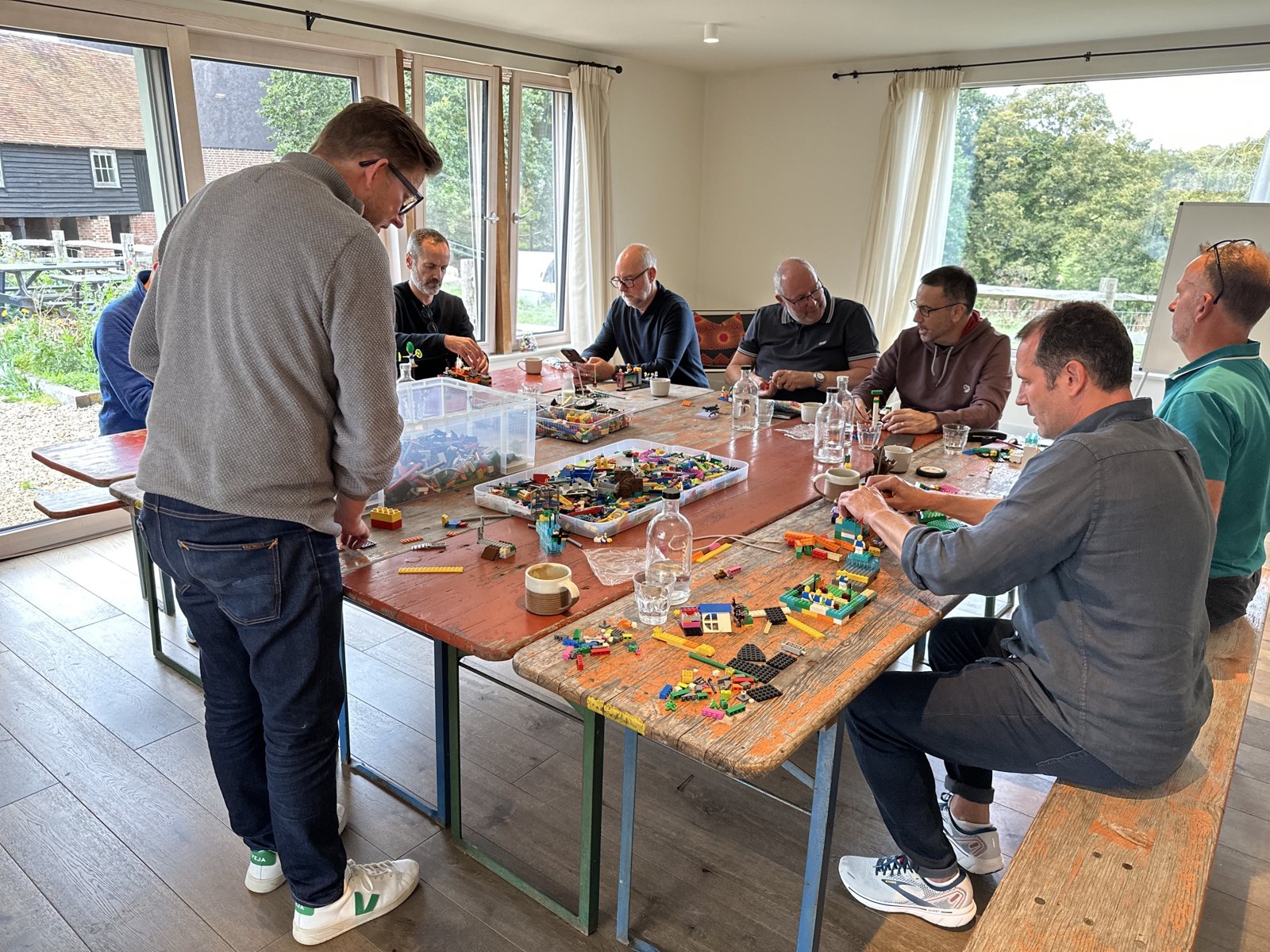 Leaders seated around one table, building and discussing LEGO models together