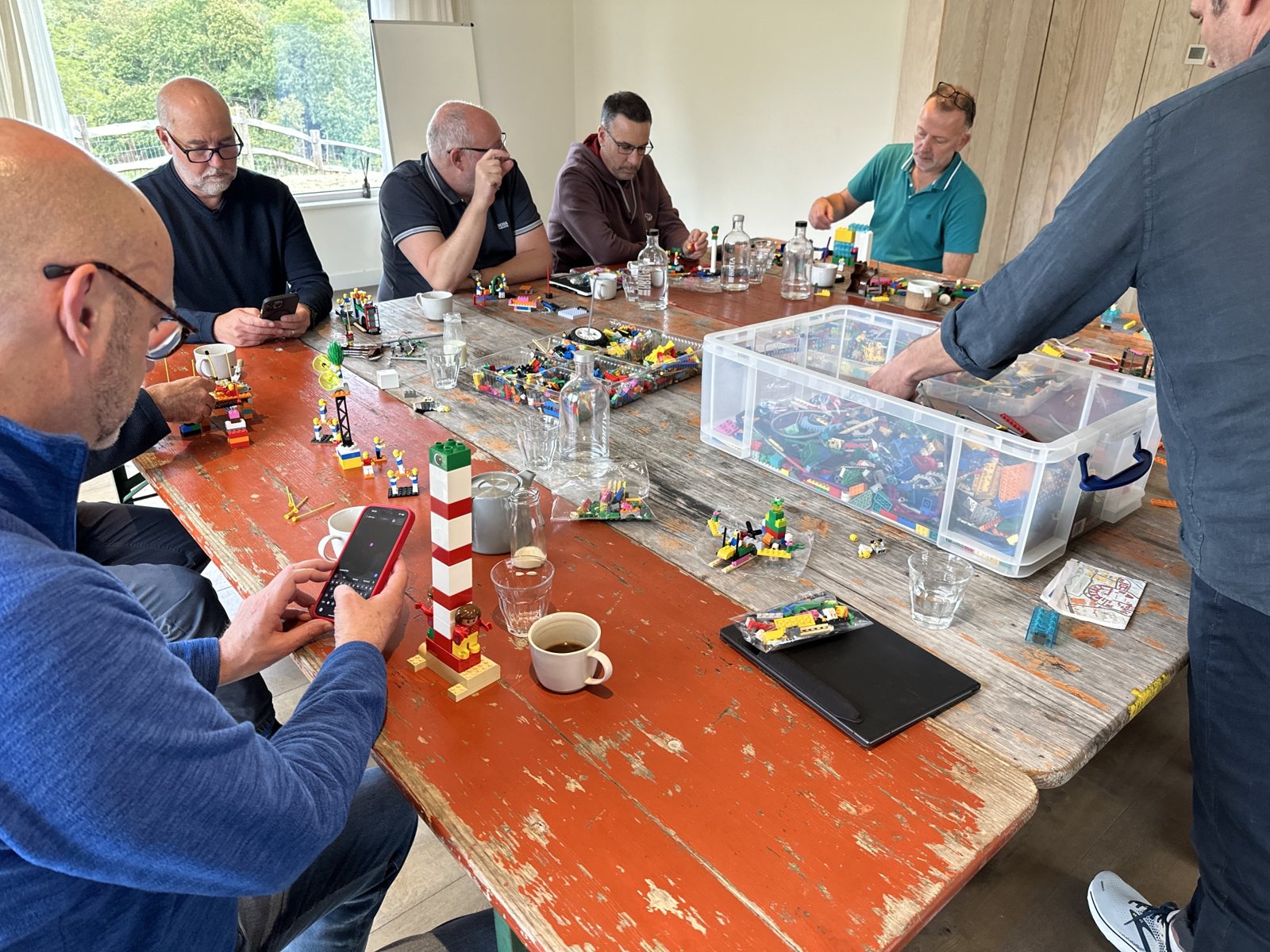 A LEGO lighthouse model built by a leader during a workshop, standing on the table among other models